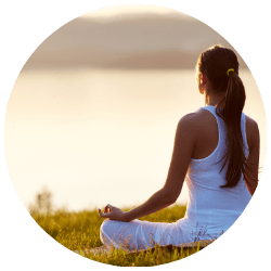 Woman meditating on a yoga mat to manage eczema stress triggers.